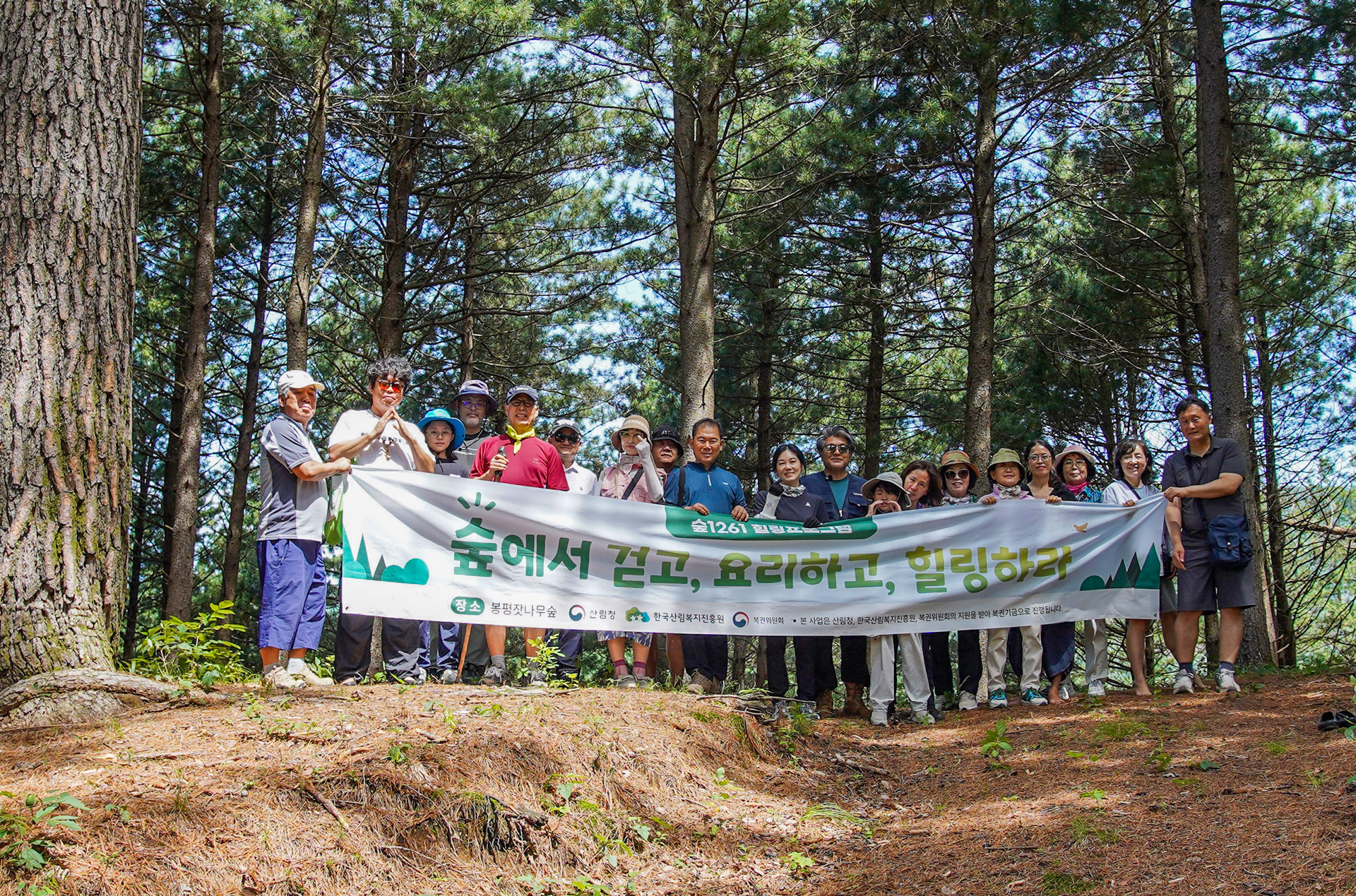 봉평 숲에서 숲1261 힐링프로그램 참가자들이 현수막을 들고 촬영한 단체 사진